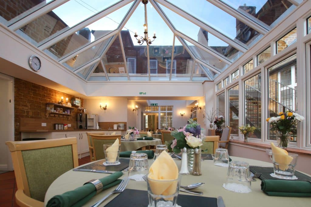 The beautiful Featherton House conservatory dining room with views of the village skyline. This is the heart of our senior living home near Banbury.