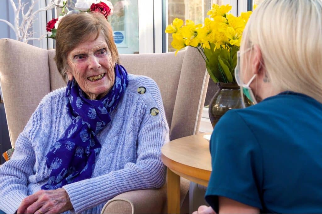 Senior living near Banbury with a smile! A Featherton House resident enjoying a chat with a team member in the sun room.