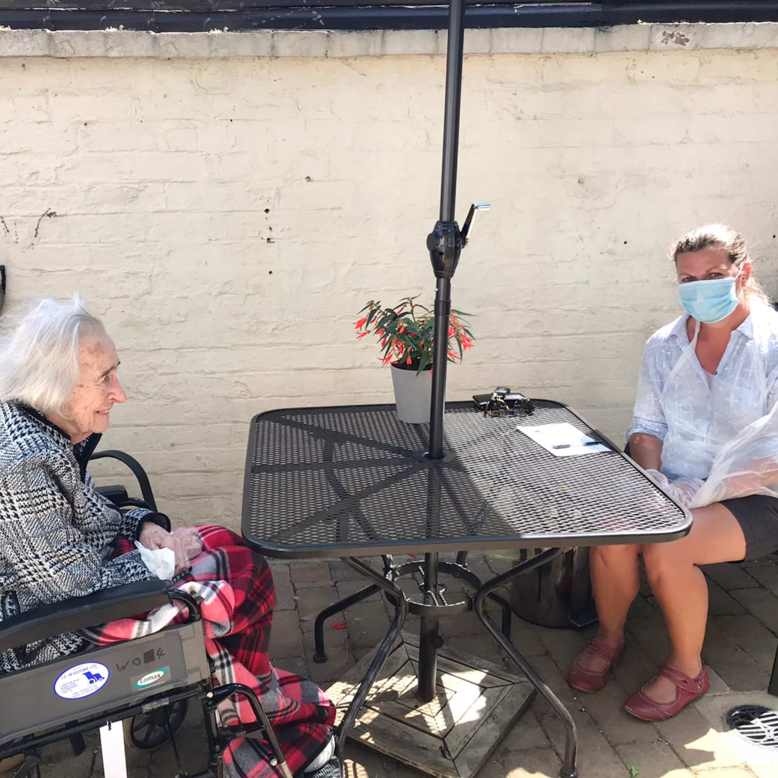 A resident and her relative in the safe outside visiting area at Featherton House Care Home in Deddington.