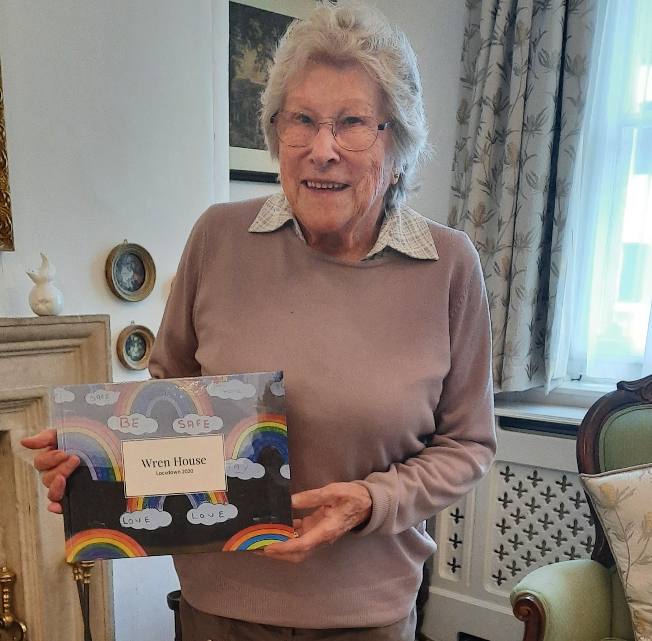 Wren House resident Pauline Taylor holding the Wren House book.