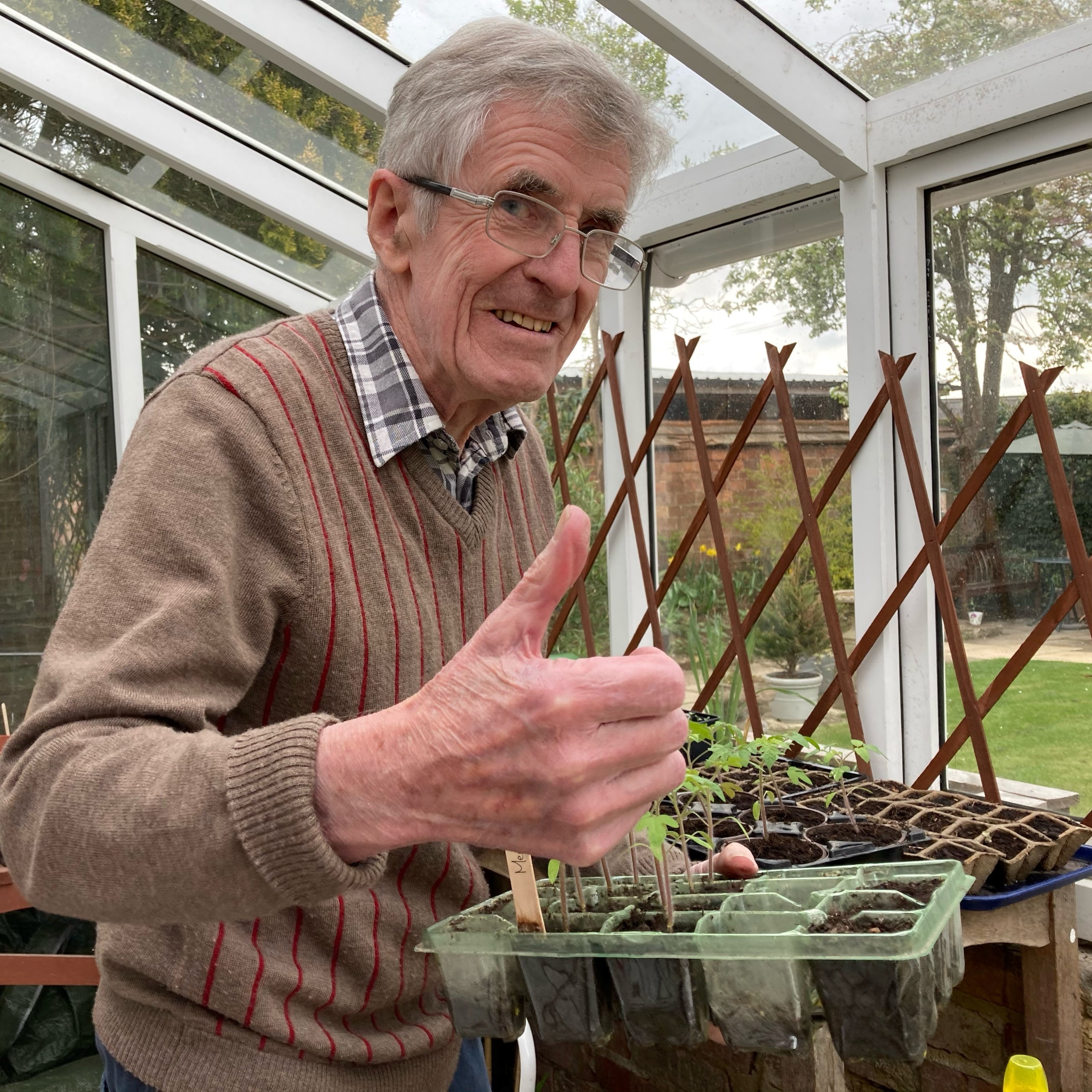 Jock Pirie, resident of Oxfordshire care home Featherton House, with a tray of seedlings in the home's rejuvenated greenhouse.
